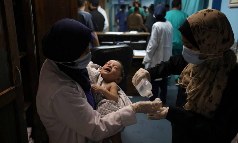 Enfermeira segura bebê de 5 meses que sobreviveu a ataque israelense que matou sua família no campo de refugiados de al-Shati, em Gaza